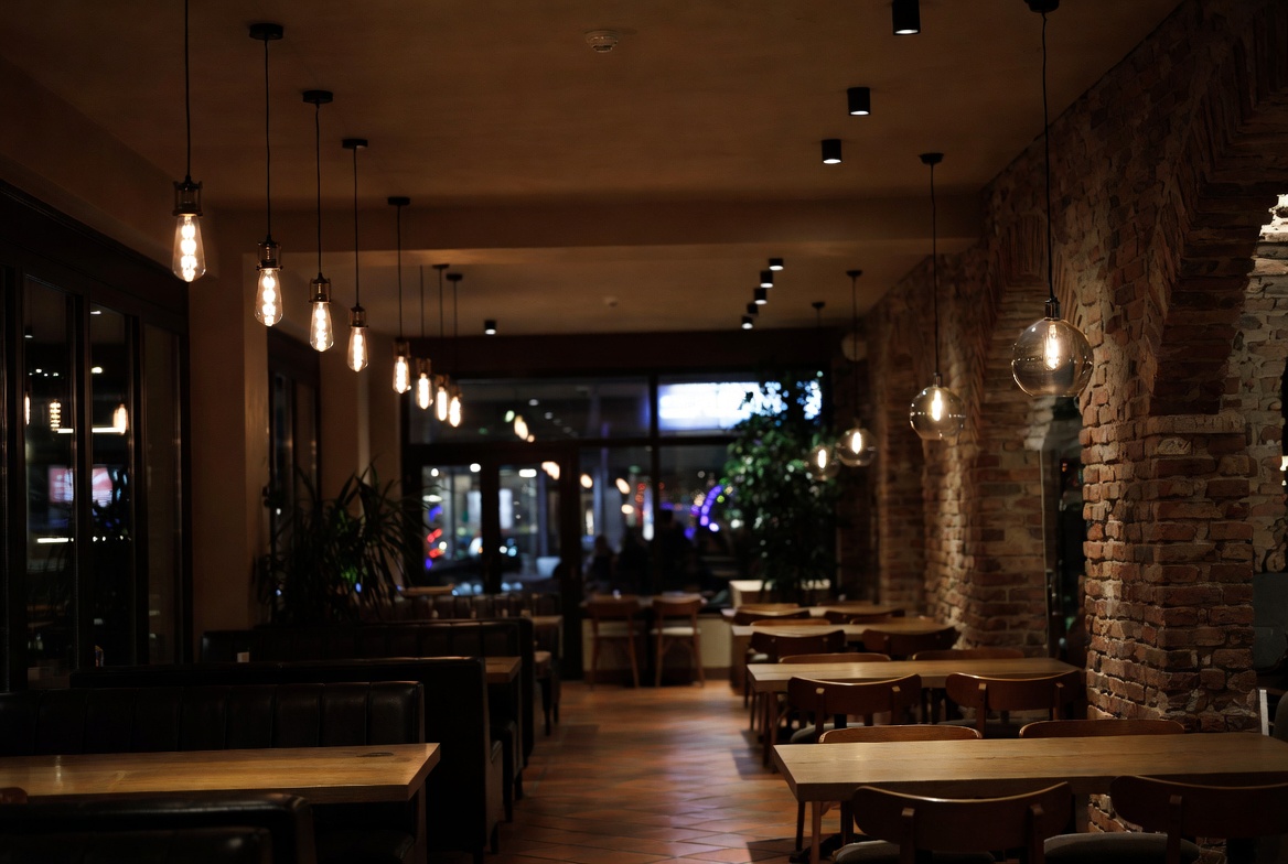 Warmes Interieur der L'Osteria mit Ziegelwand und Hängelampen